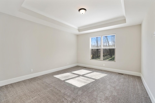 spare room featuring carpet, baseboards, a raised ceiling, and ornamental molding