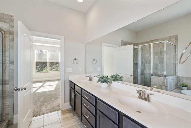 bathroom with double vanity, a stall shower, a sink, and baseboards