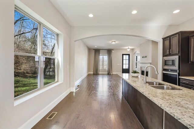 kitchen featuring arched walkways, stainless steel appliances, a sink, visible vents, and dark wood finished floors