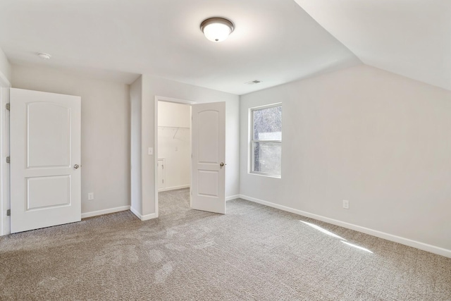 unfurnished bedroom with baseboards, visible vents, vaulted ceiling, and carpet flooring