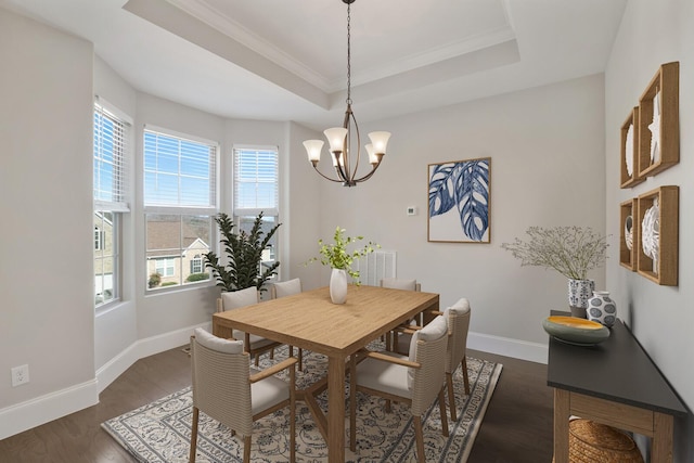 dining room featuring a tray ceiling, dark wood-type flooring, an inviting chandelier, and baseboards