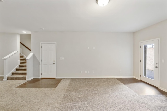 carpeted entrance foyer featuring stairway, wood finished floors, and baseboards