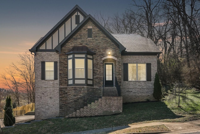 view of front of home with brick siding, a yard, stucco siding, a shingled roof, and fence