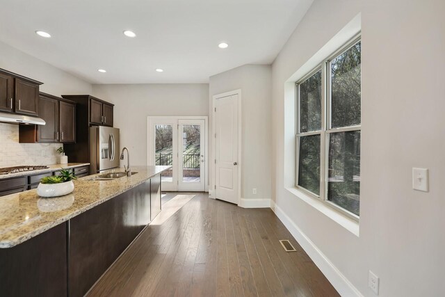 kitchen featuring light stone counters, stainless steel appliances, tasteful backsplash, visible vents, and a sink