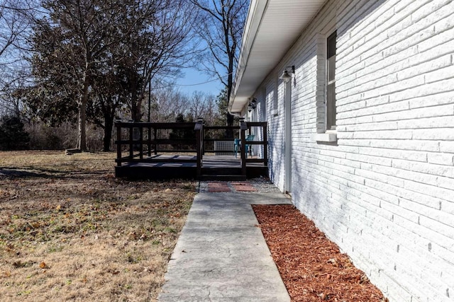 view of home's exterior featuring brick siding and a wooden deck