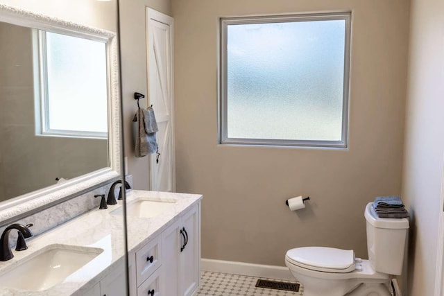 full bath with toilet, a sink, visible vents, and baseboards