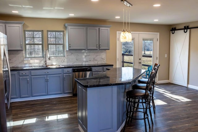 kitchen with a breakfast bar, a healthy amount of sunlight, a sink, and a barn door