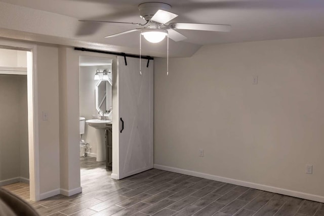 spare room with wood tiled floor, baseboards, ceiling fan, and a sink