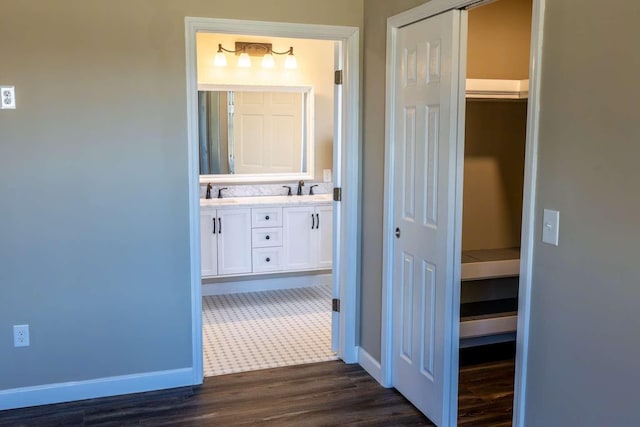 hall featuring dark wood-type flooring, a sink, and baseboards