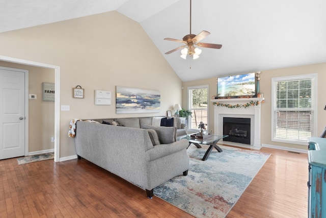 living area with a fireplace with flush hearth, high vaulted ceiling, plenty of natural light, and wood-type flooring