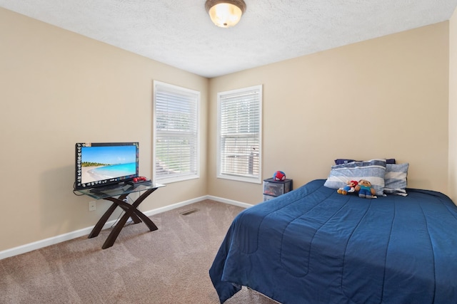 bedroom with a textured ceiling, carpet floors, visible vents, and baseboards