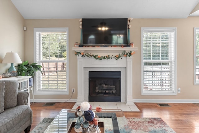 living room featuring a wealth of natural light, visible vents, a fireplace, and wood finished floors