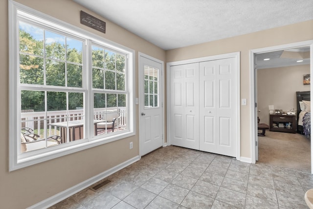 interior space featuring light tile patterned floors, baseboards, visible vents, and a textured ceiling