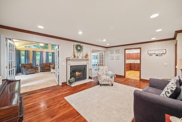 living room with ornamental molding, baseboards, a fireplace with flush hearth, and wood finished floors