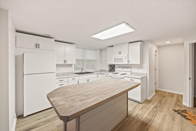 kitchen featuring white appliances, a sink, light wood-style floors, and white cabinets