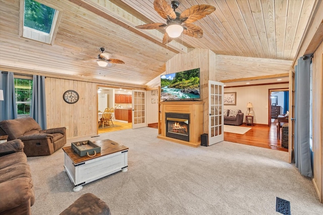 living area with lofted ceiling with skylight, carpet, wooden ceiling, and french doors