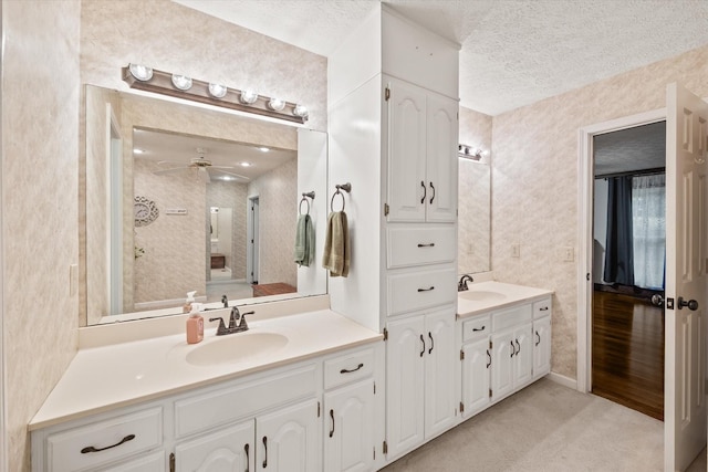 bathroom featuring two vanities, a sink, a textured ceiling, and ceiling fan