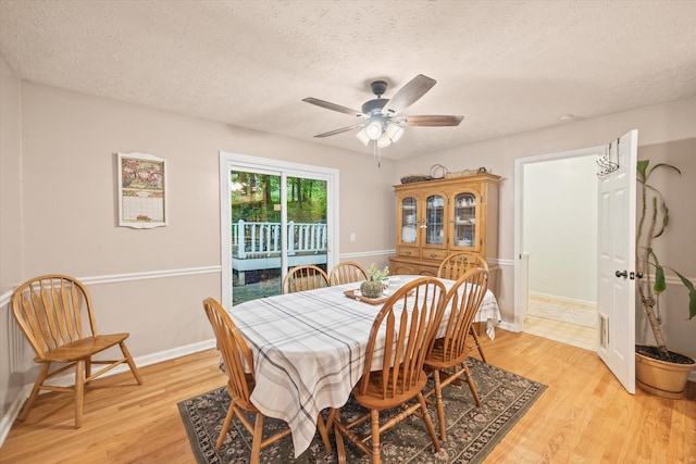 dining room featuring a textured ceiling, light wood finished floors, a ceiling fan, and baseboards