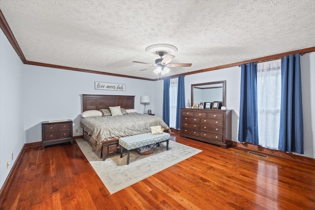 bedroom featuring visible vents, ceiling fan, wood finished floors, crown molding, and a textured ceiling