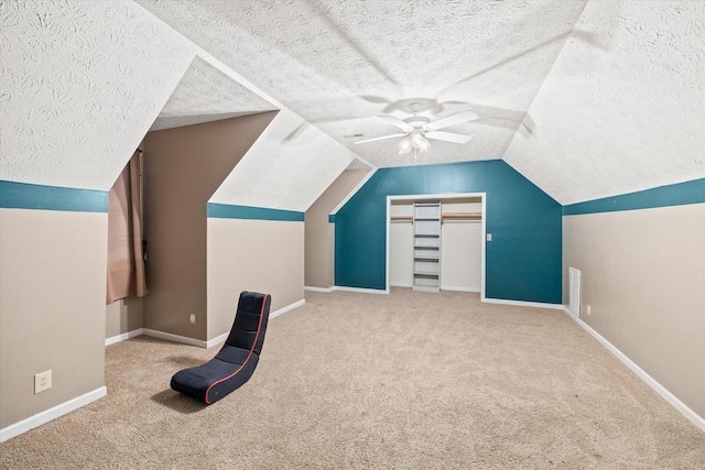 additional living space featuring baseboards, ceiling fan, vaulted ceiling, a textured ceiling, and carpet floors