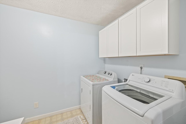 washroom featuring light floors, cabinet space, a textured ceiling, separate washer and dryer, and baseboards