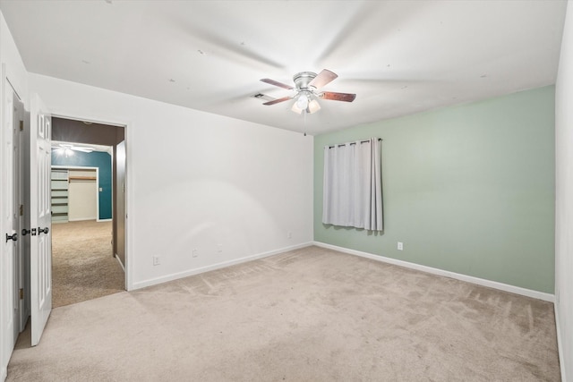 empty room featuring a ceiling fan, carpet flooring, visible vents, and baseboards