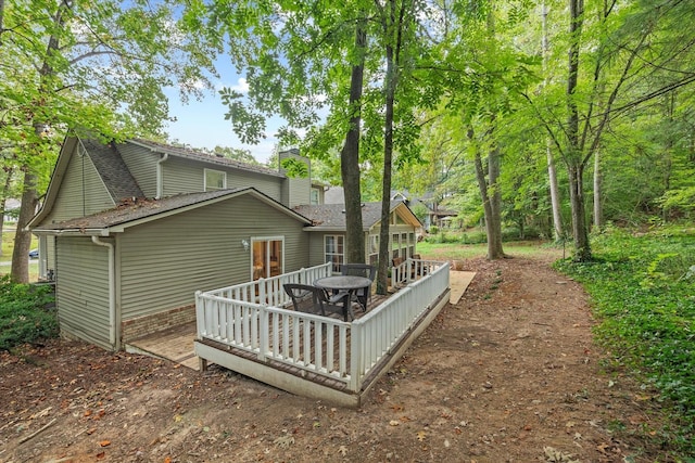 rear view of property with a shingled roof, a chimney, and a wooden deck