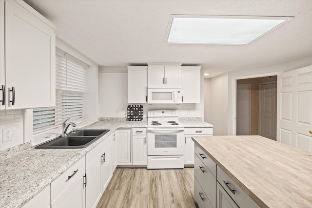 kitchen featuring tasteful backsplash, light wood-style floors, white cabinetry, a sink, and white appliances