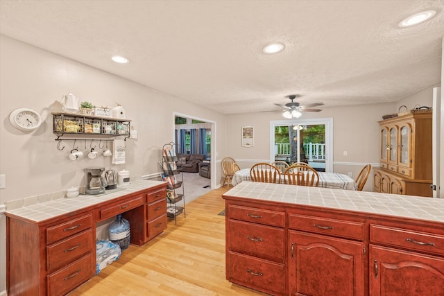 kitchen featuring tile counters, recessed lighting, a ceiling fan, a textured ceiling, and light wood-type flooring