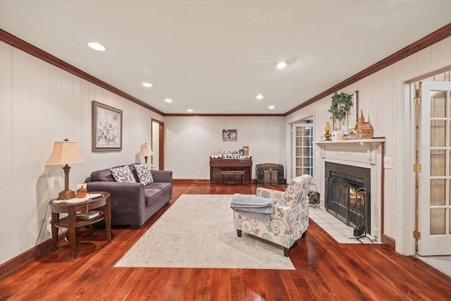 living room with recessed lighting, wood finished floors, a fireplace with flush hearth, baseboards, and ornamental molding