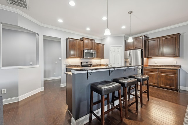 kitchen with dark wood finished floors, a breakfast bar area, stainless steel appliances, visible vents, and baseboards