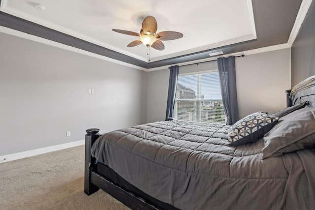 carpeted bedroom with a ceiling fan, baseboards, a raised ceiling, and crown molding