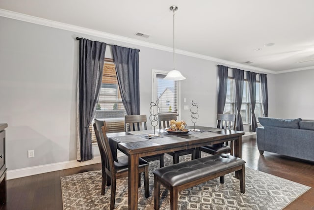 dining space featuring baseboards, wood finished floors, visible vents, and crown molding