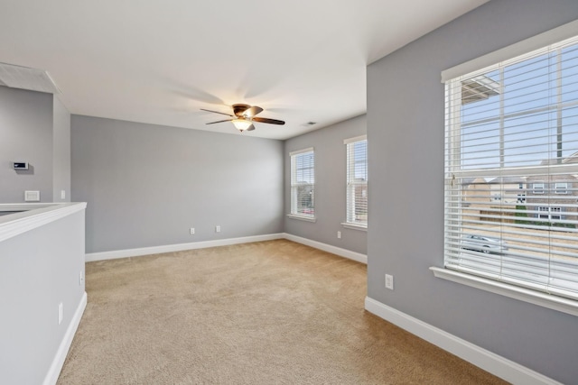 empty room with carpet floors, ceiling fan, visible vents, and baseboards