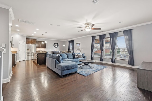 living room with dark wood-style floors, ornamental molding, visible vents, and baseboards