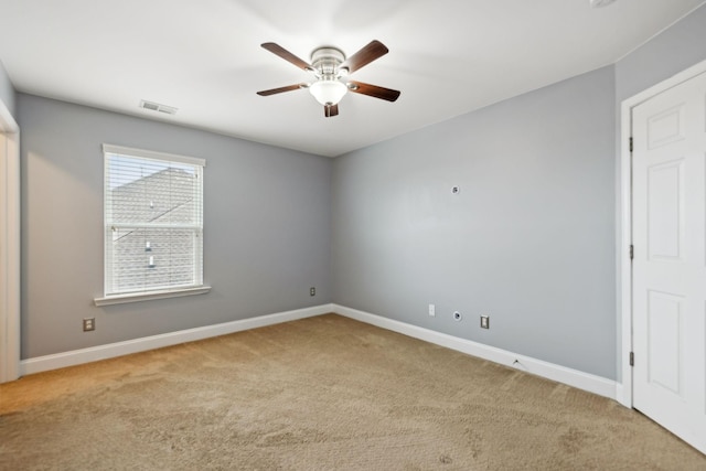 spare room with carpet floors, baseboards, visible vents, and a ceiling fan