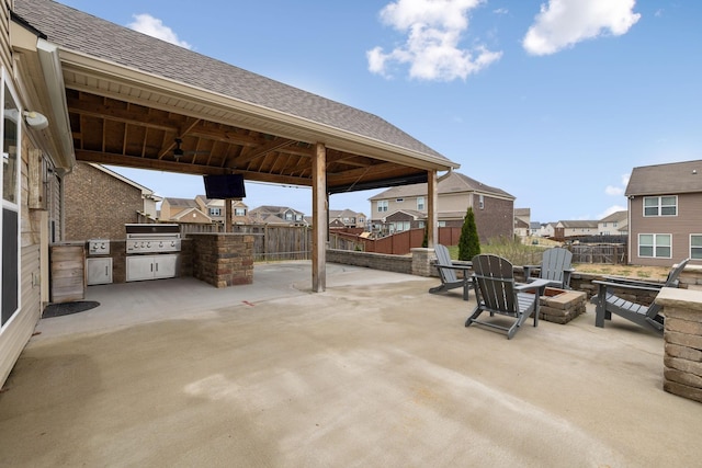 view of patio / terrace featuring an outdoor fire pit, a fenced backyard, area for grilling, exterior kitchen, and a residential view