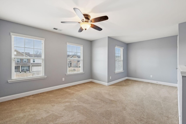 carpeted empty room with visible vents, ceiling fan, and baseboards