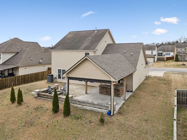 back of house with central AC unit, roof with shingles, fence, a yard, and a patio area