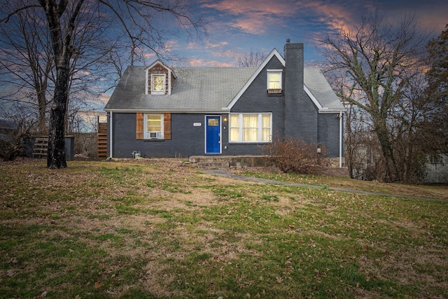 view of front of house with brick siding, a lawn, and a chimney