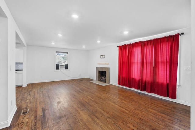 unfurnished living room featuring recessed lighting, visible vents, a fireplace with flush hearth, wood finished floors, and baseboards