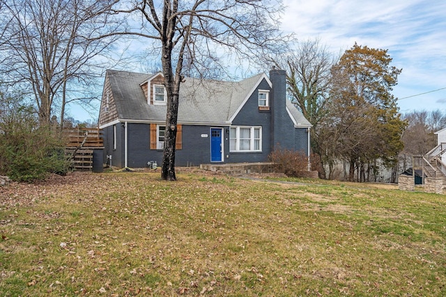 view of front of property featuring a front yard, a chimney, brick siding, and stairway