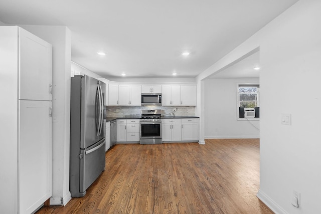 kitchen featuring dark wood finished floors, decorative backsplash, dark countertops, stainless steel appliances, and white cabinetry