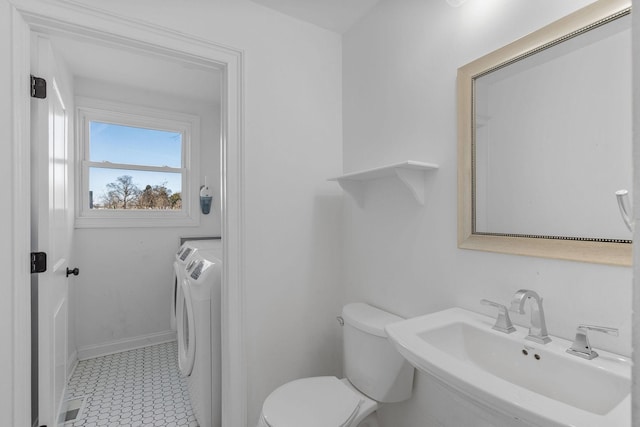 bathroom featuring visible vents, baseboards, toilet, independent washer and dryer, and a sink