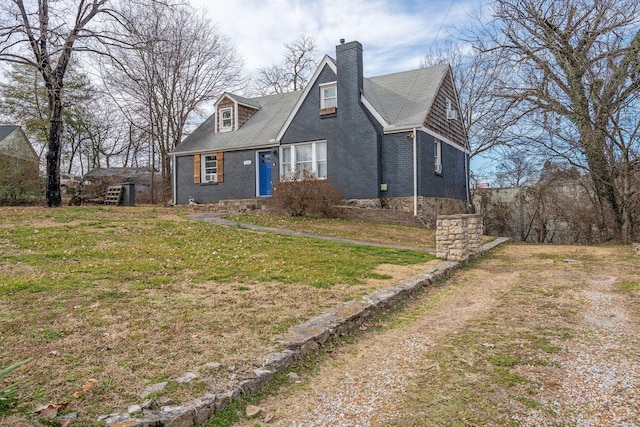 new england style home with a front yard, brick siding, and a chimney