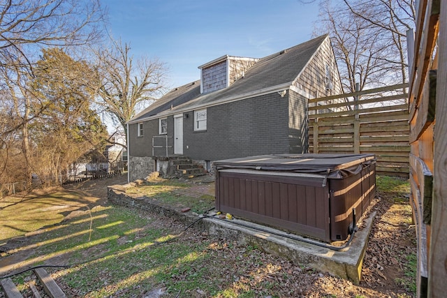 exterior space with entry steps, a hot tub, fence, cooling unit, and brick siding