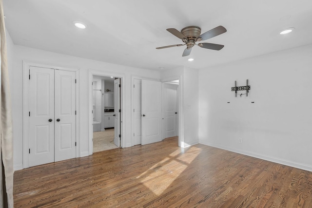 unfurnished bedroom with recessed lighting, connected bathroom, baseboards, and wood finished floors