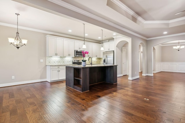 kitchen with a notable chandelier, stainless steel appliances, decorative backsplash, a tray ceiling, and dark wood finished floors