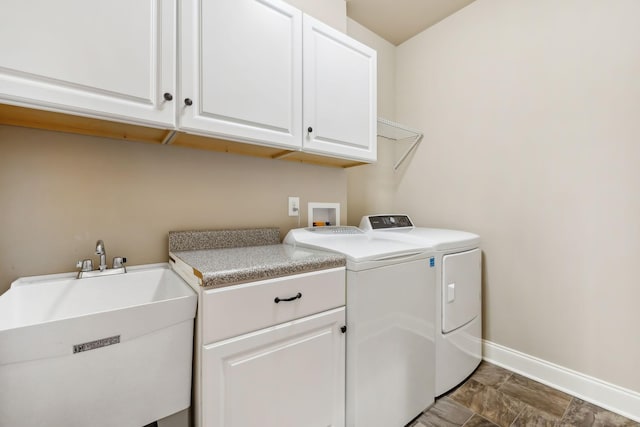 washroom with independent washer and dryer, a sink, cabinet space, and baseboards