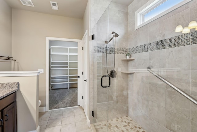 full bath featuring a stall shower, a walk in closet, visible vents, and vanity